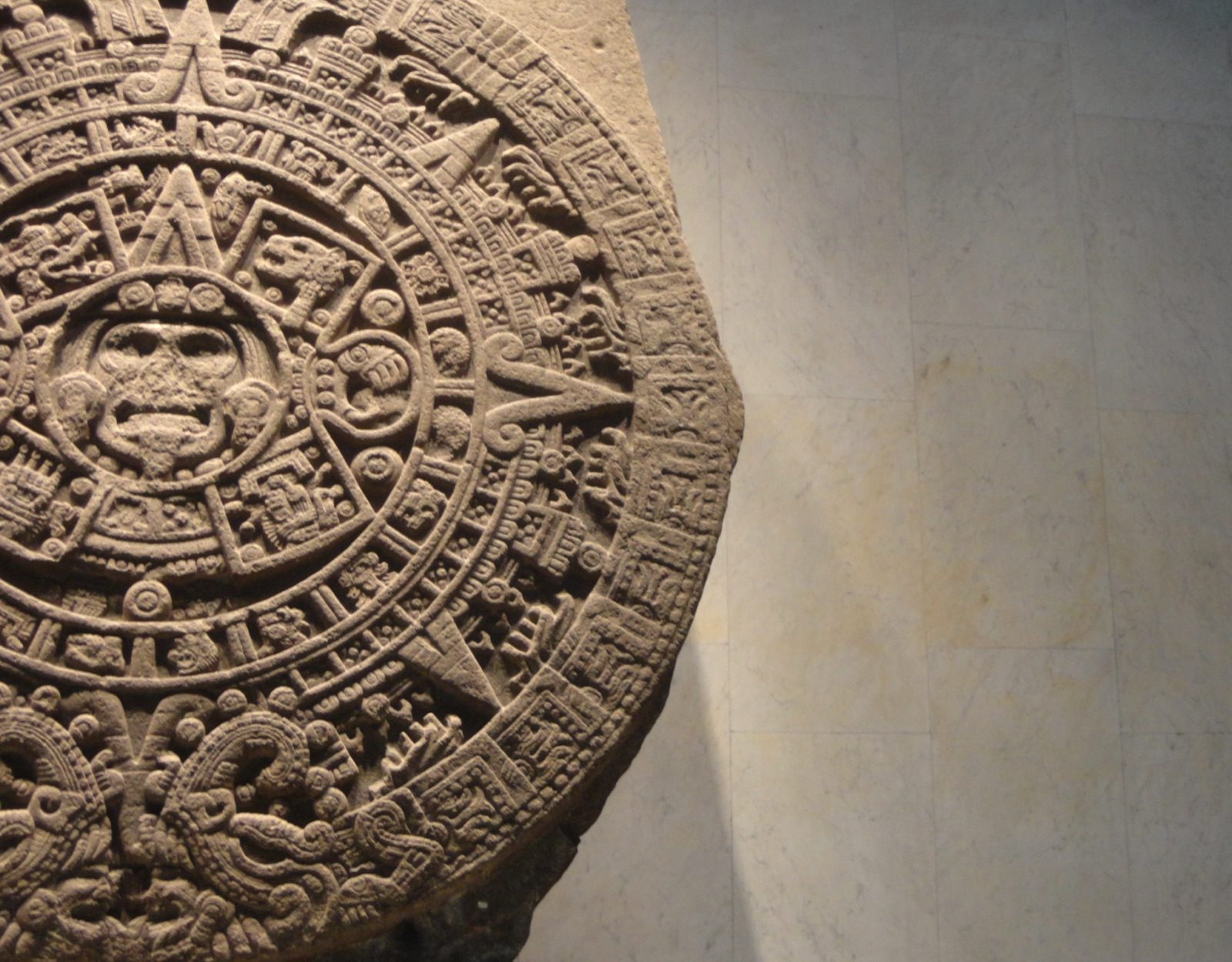 The Aztec Sun Stone, a large carved basalt disc with a central face surrounded by concentric rings of glyphs, on display at the Museo Nacional de Antropología in Mexico City.