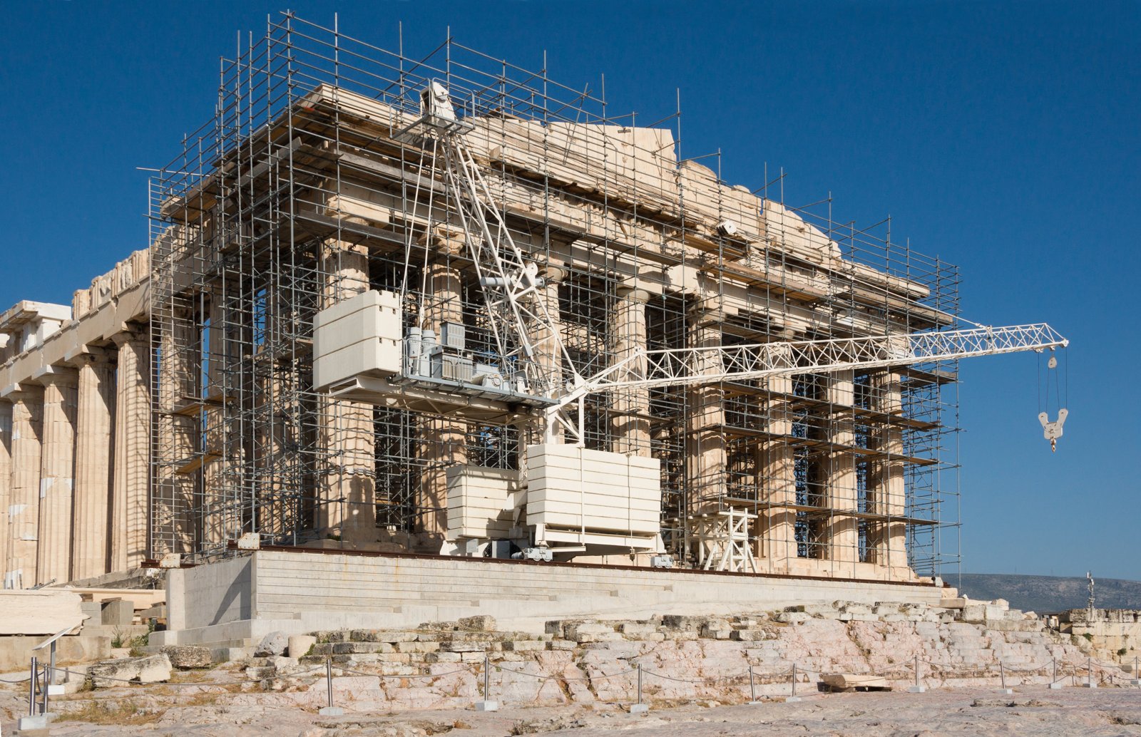 Scaffolding and a crane in front of the marble columns and west pediment of the Parthenon.